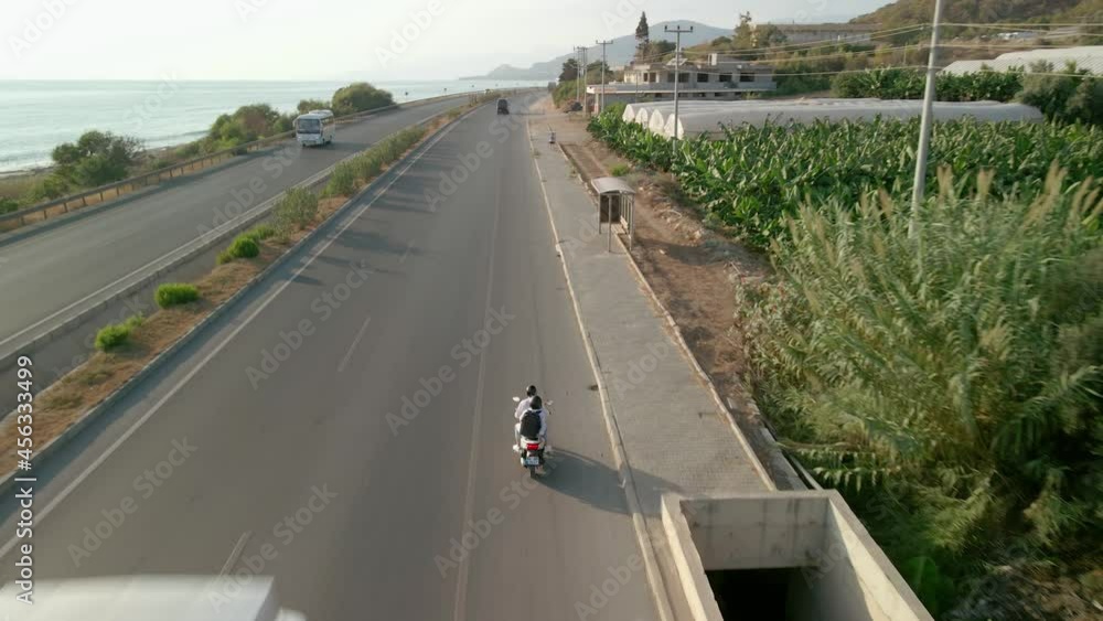 The drone follows a motorcycle that travels along the road along the sea coast. The drone follows a motorcycle that travels along the road along the sea coast.