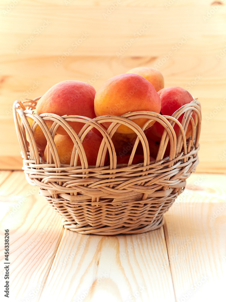 Ripe apricots in a wicker basket on a wooden table Ripe apricots in a wicker basket on a wooden table