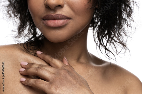 Fotografie Beautiful black woman with a smooth skin is touching her clavicle