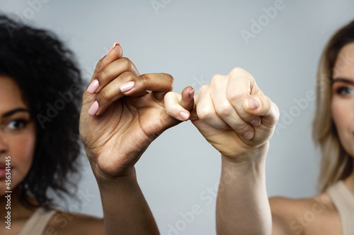 A pinky promise gesture between African and Caucasian women. photo