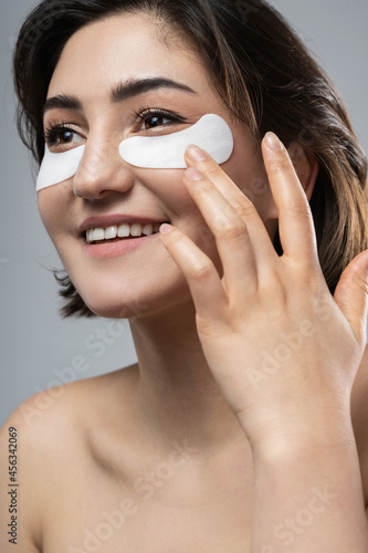 Beautiful woman with a smooth skin applying adhesive under-eyes patches for dark circles