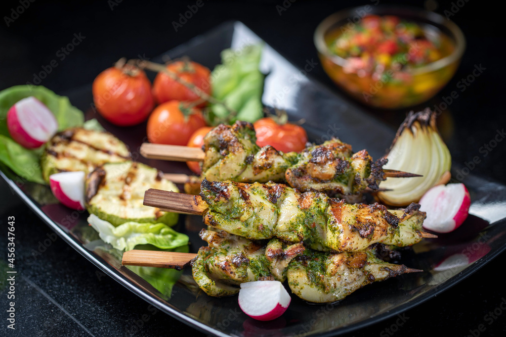 Grilled turkey skewers, skewered on wooden skewers, in a large plate decorated with herbs, zucchini and tomatoes. Grilled turkey skewers, skewered on wooden skewers, in a large plate decorated with herbs, zucchini and tomatoes.