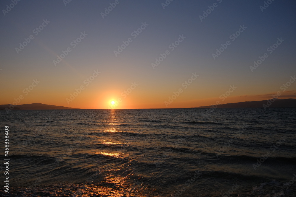 Summer and holiday photo on sea during sunset and magnificent sunlight reflection on the water with its reflection on sky