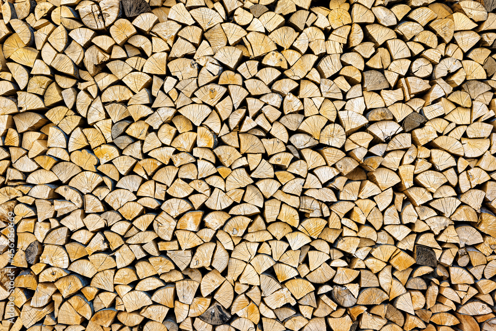 Stacked chopped wood close-up texture. Firewood storage background. Stocks of wooden logs. Chopping wood for a fireplace. Woodpile with firewood with visible wooden texture. Stacked chopped wood close-up texture. Firewood storage background. Stocks of wooden logs. Chopping wood for a fireplace. Woodpile with firewood with visible wooden texture.