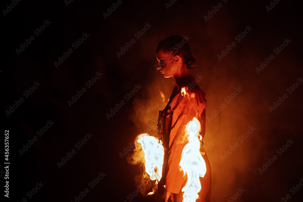 a dangerous and beautiful fireshow in the dark. artists in costumes of mythological creatures hold burning staffs and fans in their hands. juggling with fire