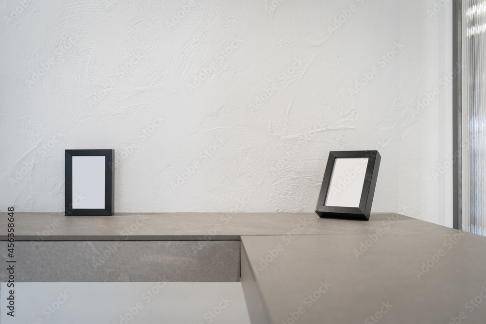 Beautiful black wooden picture frame with blank for copy space for text and advertising on brown ceramic shelve decoration on white wall rough surface textured background. Beautiful black wooden picture frame with blank for copy space for text and advertising on brown ceramic shelve decoration on white wall rough surface textured background.
