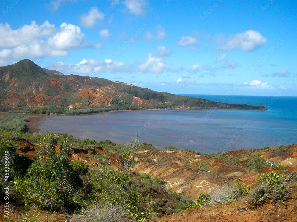 Obraz premium Green-orange-red-brown landscape with lake and mountains and blue sky.