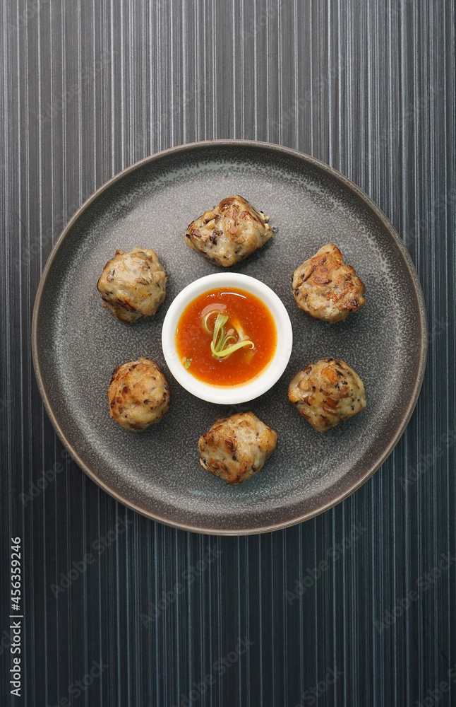 deep fried pork meatball with scallop and mushroom and chilli dip on dark grey wood background dim sum menu deep fried pork meatball with scallop and mushroom and chilli dip on dark grey wood background dim sum menu
