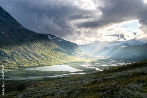 Fototapeta Naklejka Na Ścianę i Meble -  Remote harsh arctic landscape in rough weather in Sarek national park, Swedish Lapland. Heavy clouds with rays of light coming through.