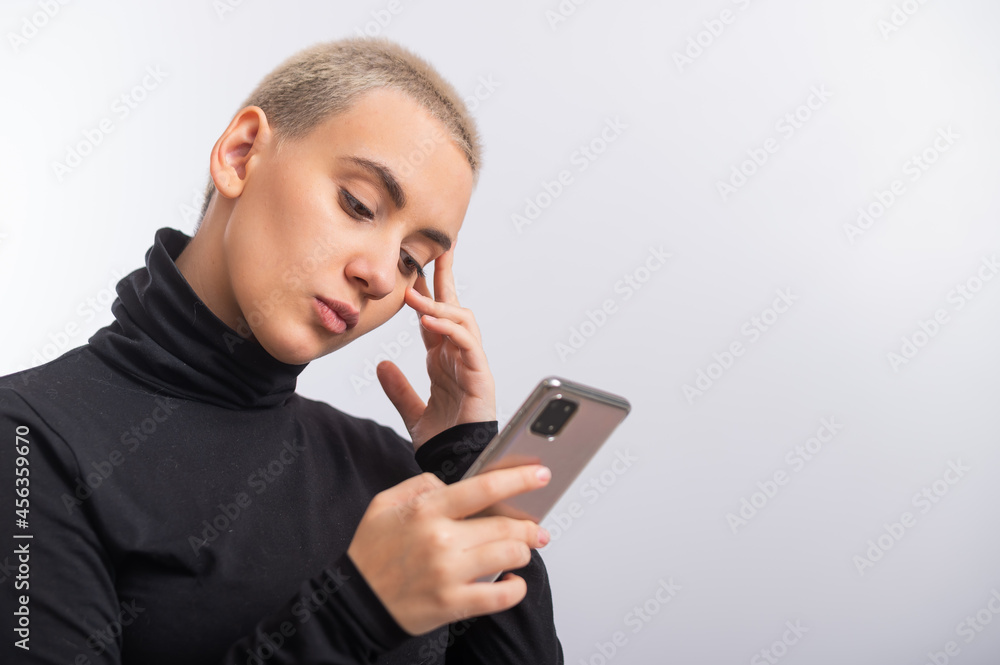 Young caucasian woman with short hair uses a smartphone on a white background. Young caucasian woman with short hair uses a smartphone on a white background.