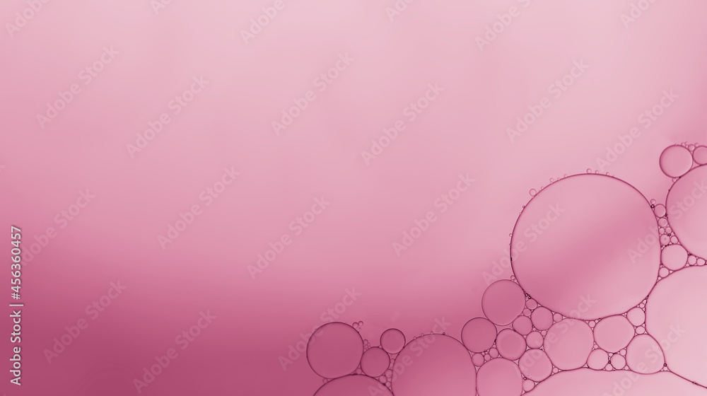 Oil bubble on water surface with pink-purple gradient background.