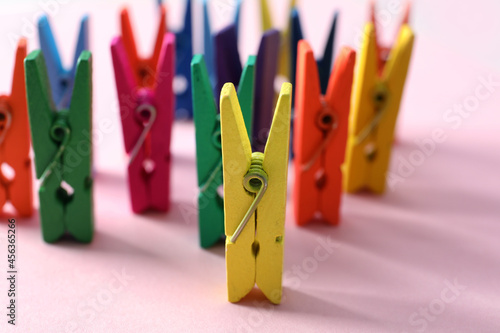 Many different colorful clothes pins on pink background. Diversity concept