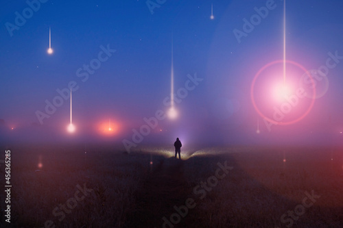 UFO concept. Glowing orbs, floating above a misty field at night. With a silhoutted figure looking at the lights.