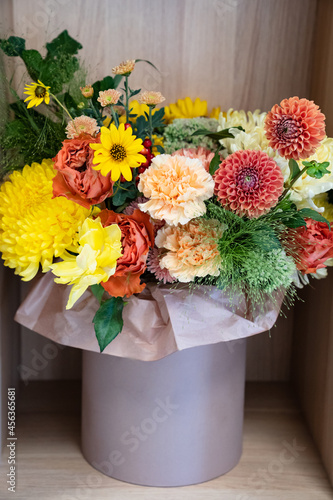 a bouquet of yellow and orange flowers in a hat box on a shelf in the closet. 