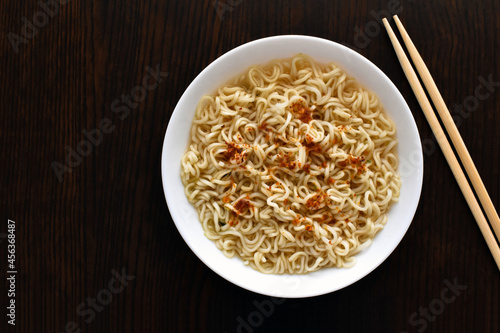 Instant noodles with chopsticks in a white bowl.  Flat lay top view photo.  Food from above.