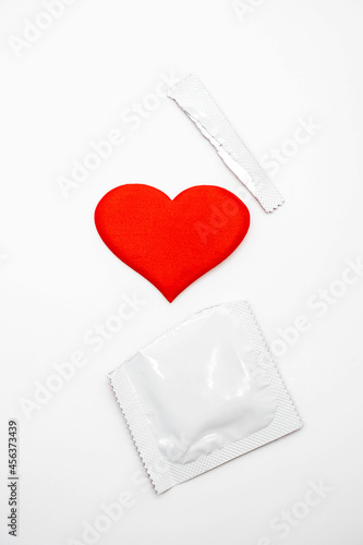  White blank condom packed and red heart shape. Empty space for text, mock-up. Safe sex concept.