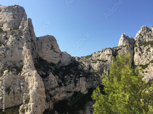 View of typical Calanques cliff with sparse vegetation seen from the footpath leading from Luminy to the Calanque de Sugiton in Marseille, France. The Aiguille de Sugiton peak can be seen on the left.