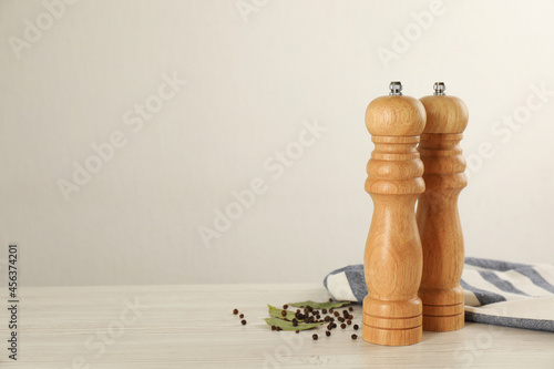 Wooden salt and pepper shakers with napkin on table against white background, space for text. Spice mill