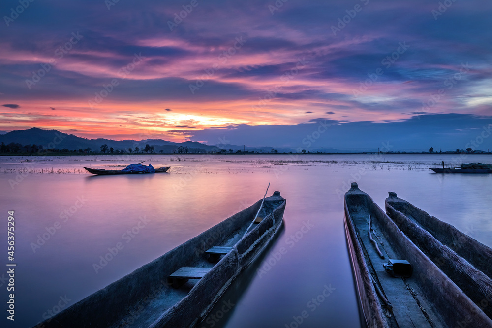 Obraz premium Mountain landscape, lake and mountain range, large lake and boat. Beautiful sunset reflected in the Lak lake, Buon Me Thuot, Vietnam