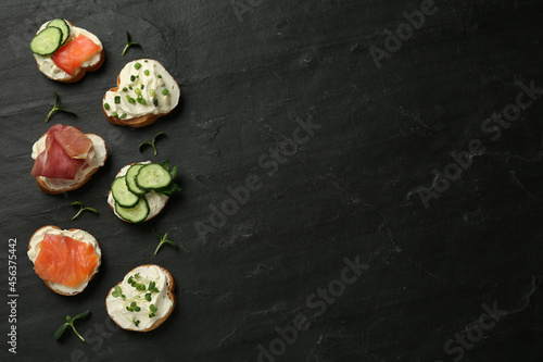 Delicious sandwiches with cream cheese and other ingredients on black table, flat lay. Space for text