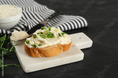 Delicious sandwich with cream cheese and microgreens on black table