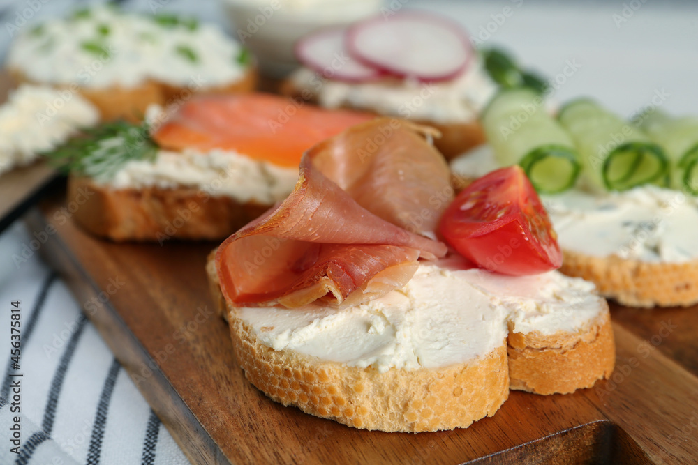Toasted bread with cream cheese and different toppings on wooden board, closeup Toasted bread with cream cheese and different toppings on wooden board, closeup
