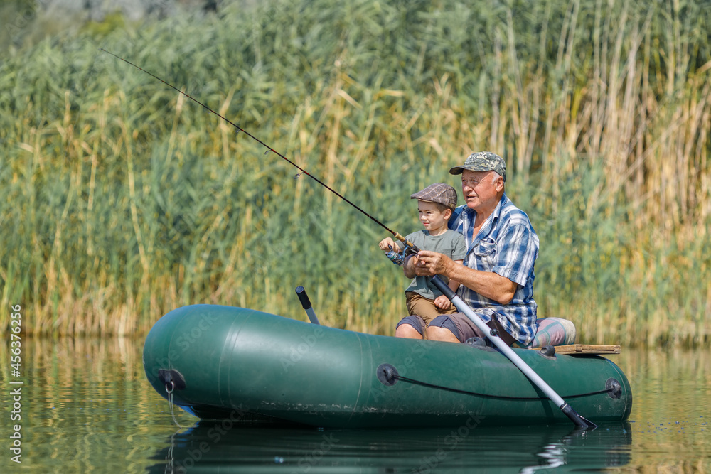 grandfather with grandson together fishing from inflatable boat grandfather with grandson together fishing from inflatable boat