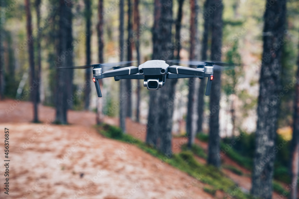 Modern Drone with camera flying in the forest. Modern Drone with camera flying in the forest.