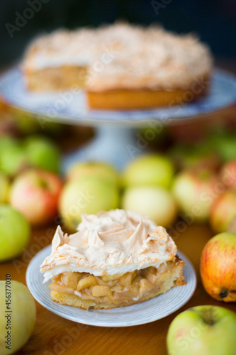 Apple pie with meringue on the top surrounded with green and red autumn apples
