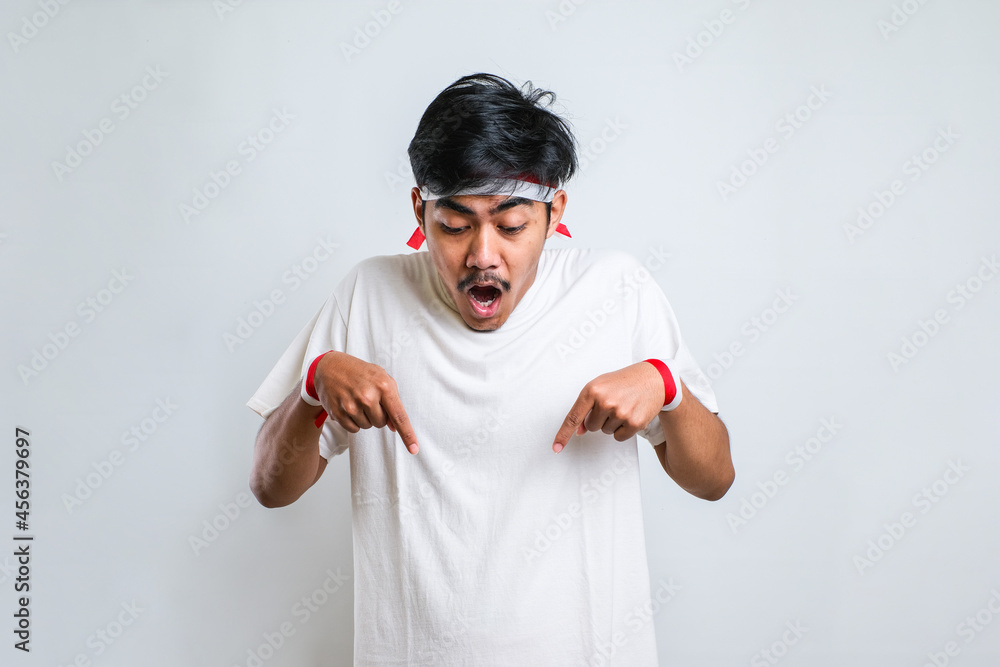 Naklejka premium Man wearing casual shirt standing pointing down with fingers showing advertisement, surprised face and open mouth
