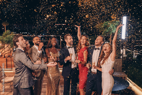 Photography Group of happy people in formalwear having fun together with confetti flying all