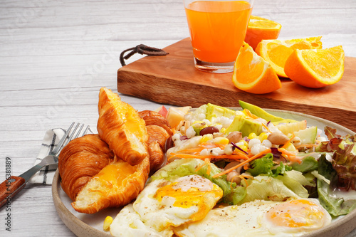 Croissant, fried egg, fresh green salad with fresh orange juice, breakfast