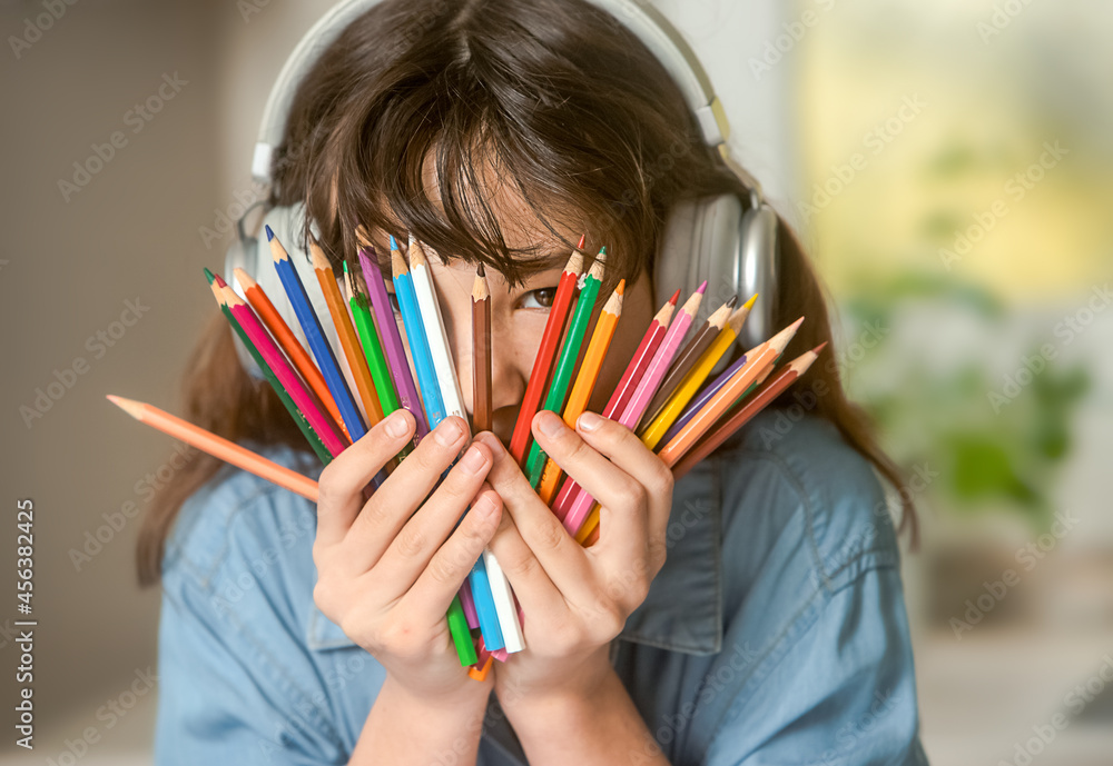 portrait of pre-teenager girl on holding pencils and listening music using headset portrait of pre-teenager girl on holding pencils and listening music using headset
