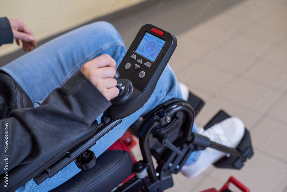 Close-up of a female hand on the control handle of an electric wheelchair