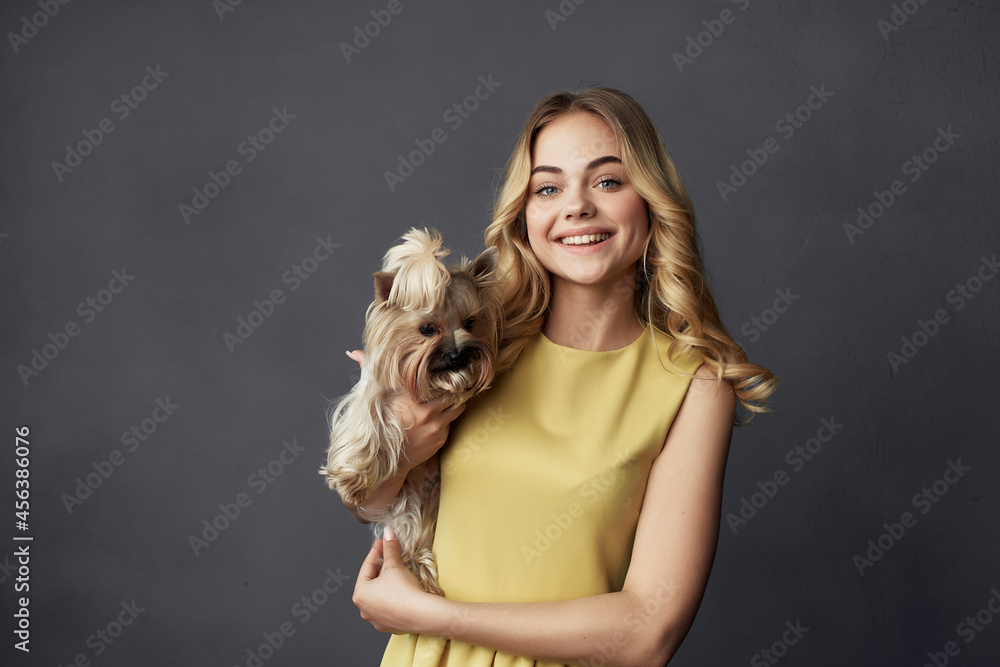 cheerful blonde in a yellow dress little purebred dog fun