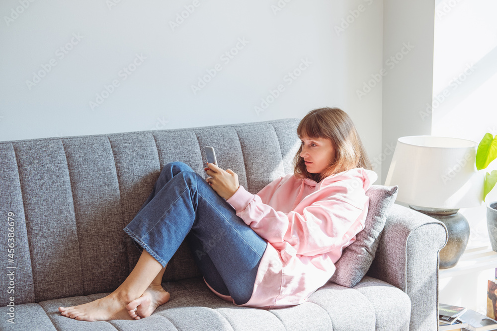Young woman using mobile phone on couch. Young woman using mobile phone on couch.