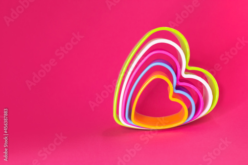 Multicolored heart shaped cookie cutters on a pink background