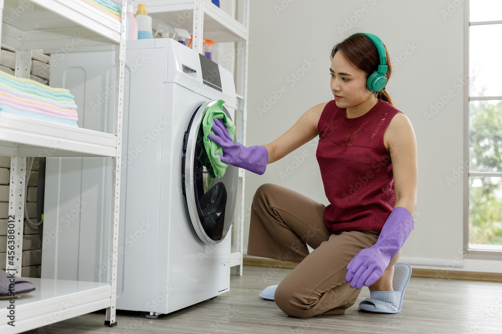 Happy housewife cleaning laundry washing machine at home and listening music Happy housewife cleaning laundry washing machine at home and listening music