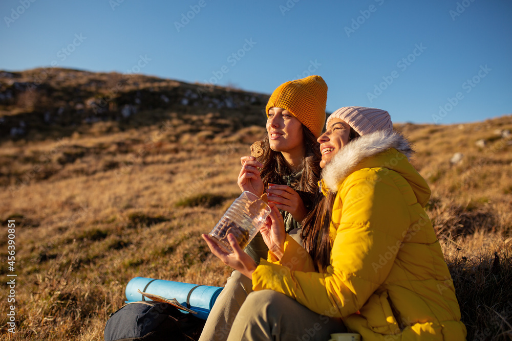 Fototapeta premium Two women on hiking trip eating cookies
