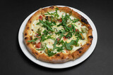 closeup of seafood pizza with shrimp, mussels and arugula on black background