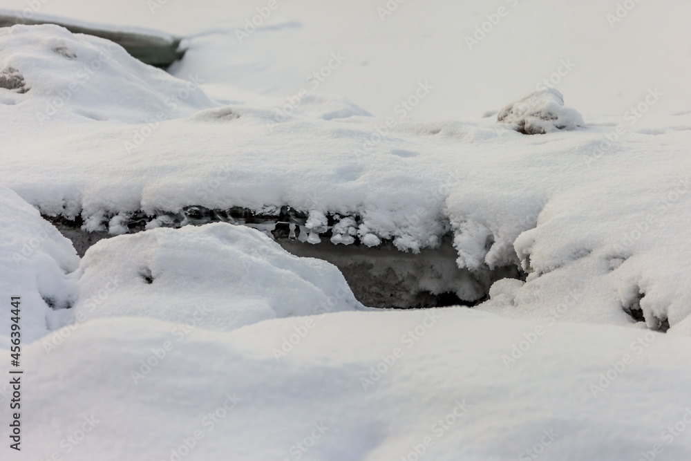 Icicles and frost on a snow-covered frozen river