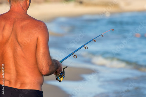 A fisherman is fishing on a spinning rod on the seashore. Active rest in the tropics.