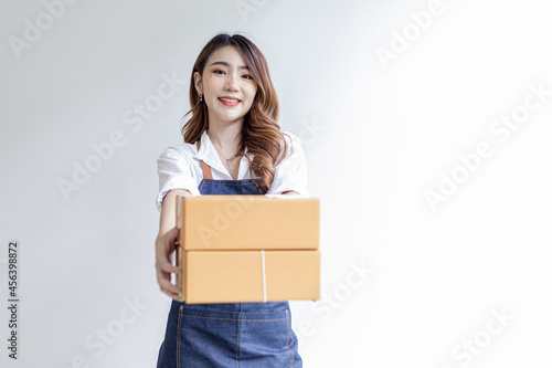 Asian woman standing holding parcel boxes, she owns an online store, she packs and ships through a private transport company. Online selling and online shopping concepts. © kamiphotos