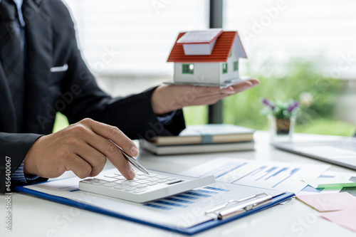 Billede på lærred Businessman presses a calculator to calculate the amount on a housing estate sal