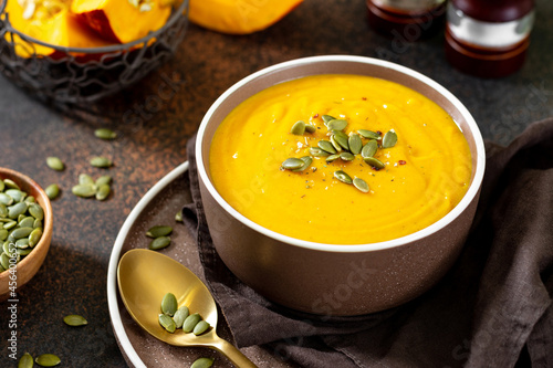 Pumpkin cream soup with seeds close-up on a dark background. Traditional autumn vegetarian dish on a dark background