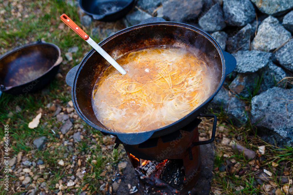 noodle soup in a large cauldron on fire noodle soup in a large cauldron on fire