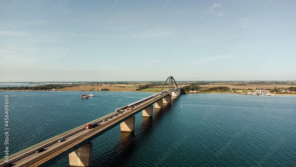 Luftaufnahme einer großen Brücke mit Verkehr über einer Meerenge mit blauem Wasser und vielen Schiffen
