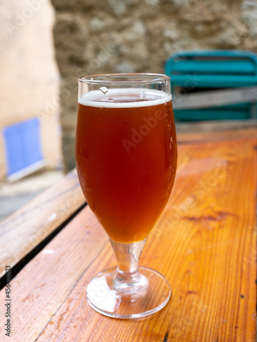 Glass of craft dark honey beer from brewery served outdoor