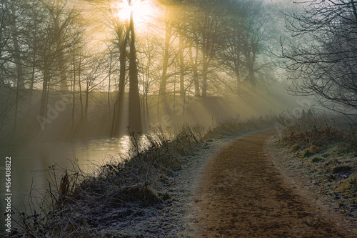 Misty Sun Rays on Frozen Canal and Towpath with Two Companions Walking photo