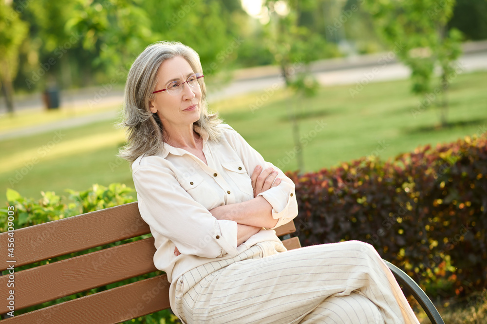 Confident adult woman sitting on park bench Confident adult woman sitting on park bench